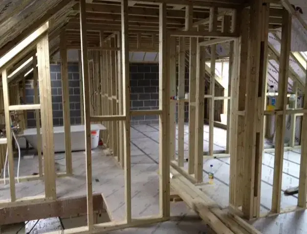 Loft conversion under construction, with new timber studwork forming the rooms, insulated floor decking and a freestanding bath already set in place