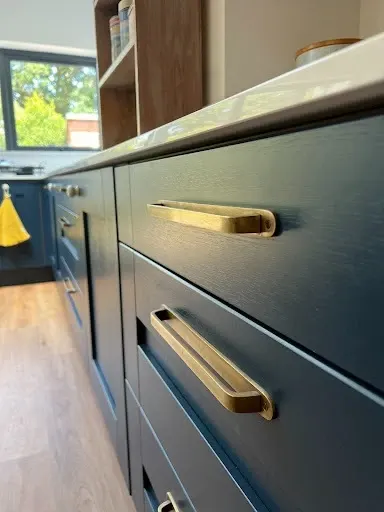 Close-up of painted navy drawer fronts with brushed brass bar handles
