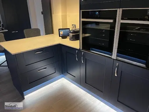 Navy shaker units with a stacked pair of built-in ovens and LED plinth lighting